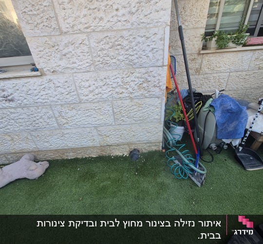 קיר אבן עם צינור וכלים בחצר